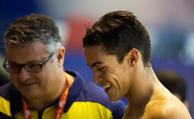 Israel Oliver y su entrenador, José Luis Vaquero, sonríen tras ganar la medalla de bronce en 100 mariposa.